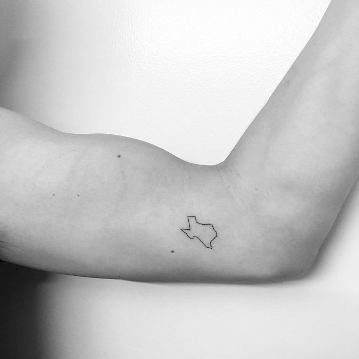 Minimalist Texas travel tattoo on inner arm.