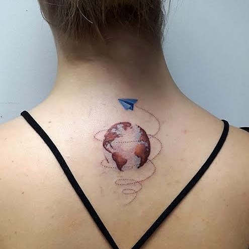 Travel tattoo of a globe with a paper plane on a woman's back, symbolizing wanderlust and adventure.