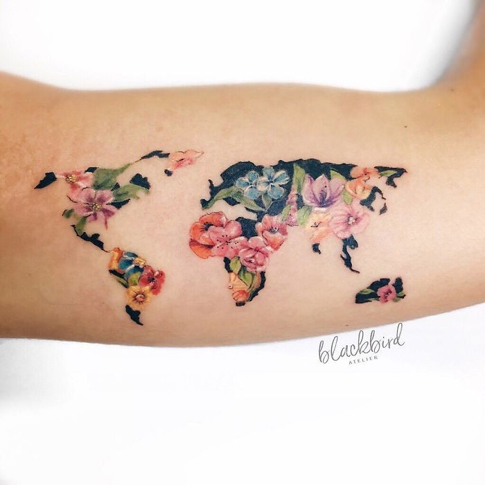 Floral world map tattoo on an arm, symbolizing travel inspirations and wanderlust dreams.