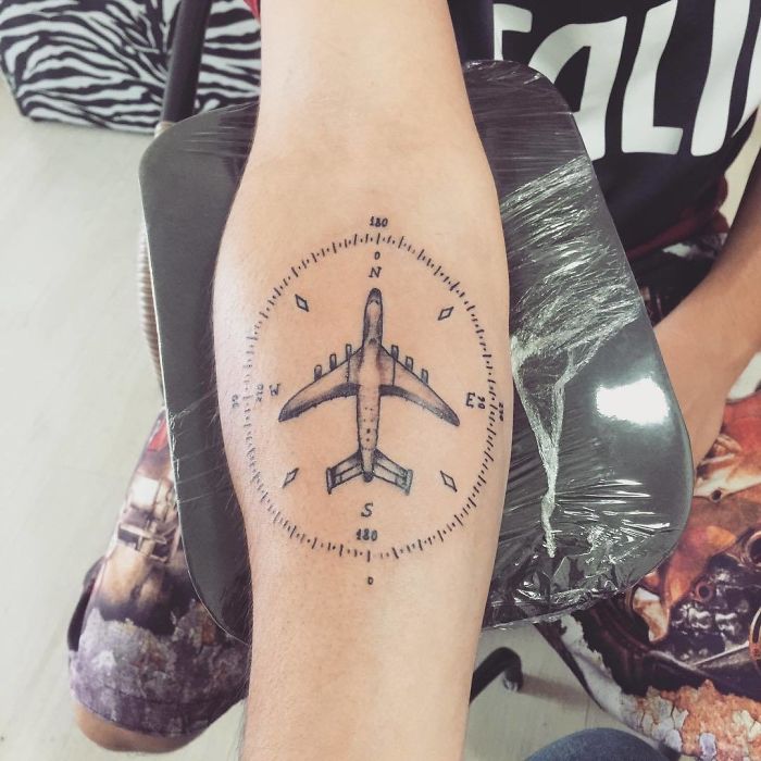 Travel tattoo of an airplane compass design on forearm, symbolizing adventure and exploration.