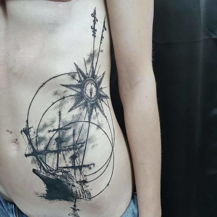 Travel tattoo featuring a ship and compass, evoking exploration and adventure.