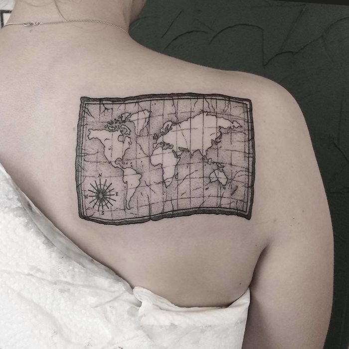 World map tattoo on upper back symbolizes travel inspiration and wanderlust.