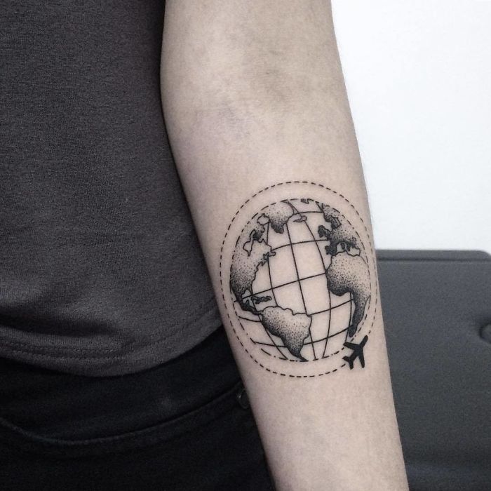 Travel tattoo of a globe with airplane on forearm, symbolizing wanderlust and adventure.