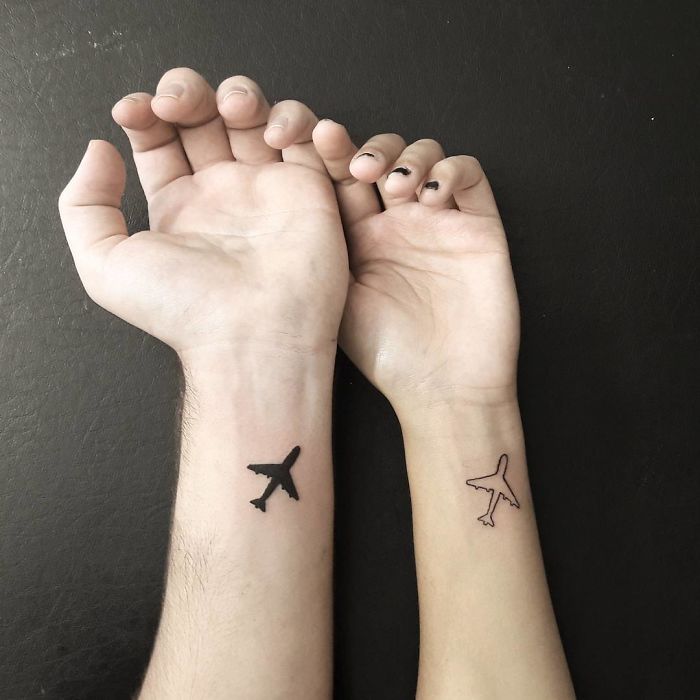 Airplane travel tattoos on wrists, inspiring wanderlust and adventure.