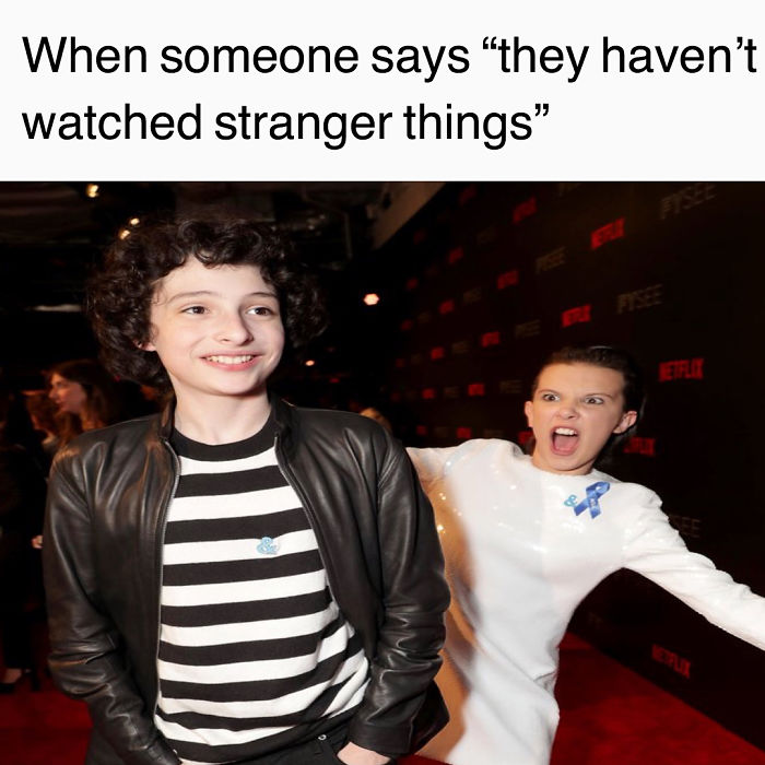 "Two actors from Stranger Things at a red carpet event, one smiling and the other making a playful expression."