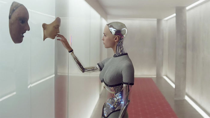 Scene from Ex Machina movie showing a female robot interacting with faces on a wall for 118 fun facts about movies.