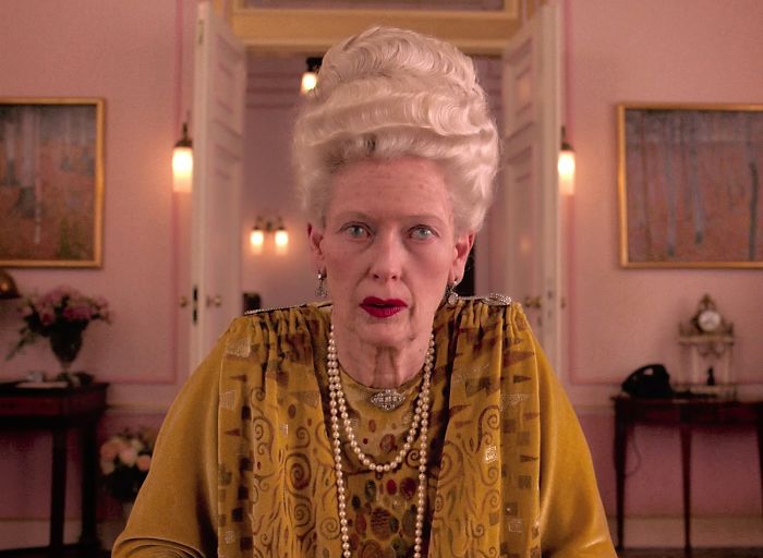 Scene from The Grand Budapest Hotel movie featuring an elderly woman in period costume for fun facts about movies.