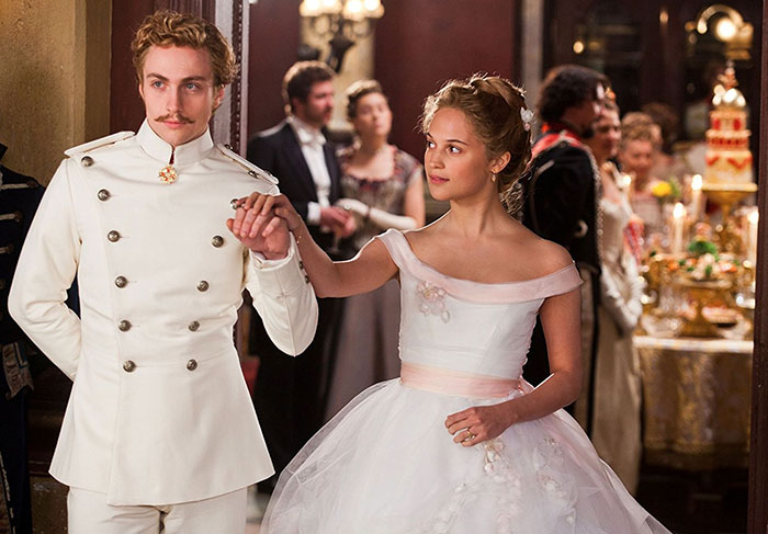 Scene from Anna Karenina movie showing a man in a white uniform and a woman in a white gown at a formal event.