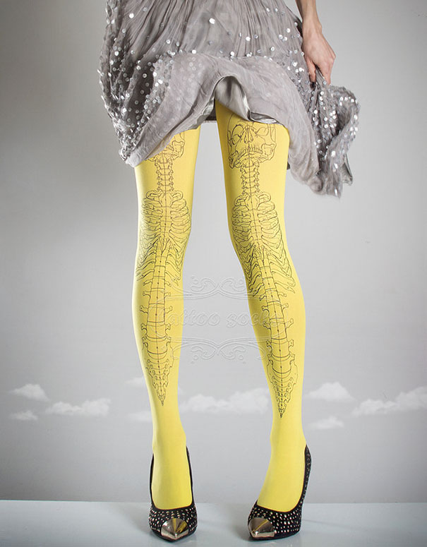 Yellow tattoo socks with a skeleton design worn with a gray skirt and black high-heeled shoes.
