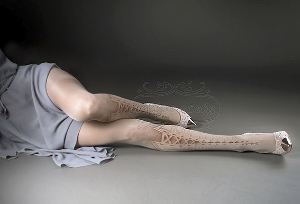Person wearing tattoo socks with lace detailing, lying on a gray surface.