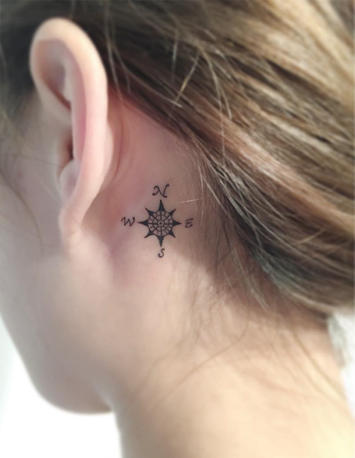 Compass tattoo behind the ear, symbolizing travel inspiration and wanderlust.