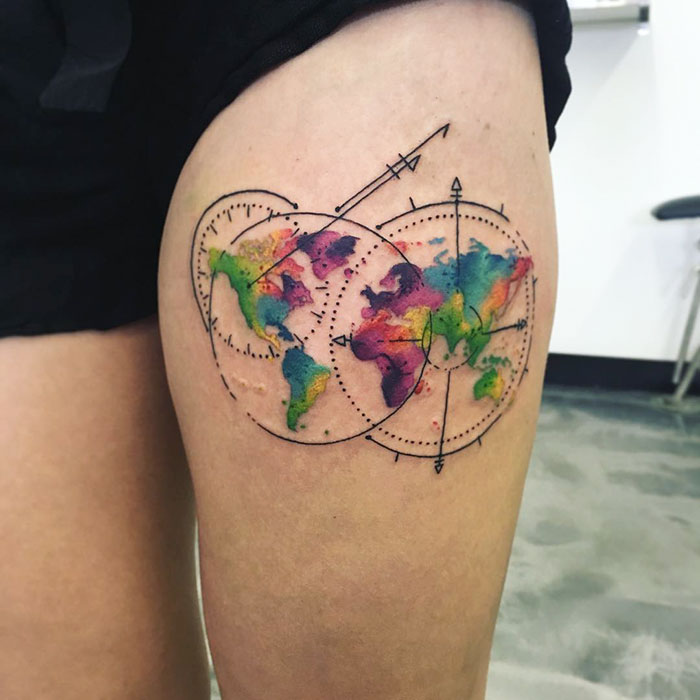 Colorful world map tattoo on thigh, inspiring travel dreams.