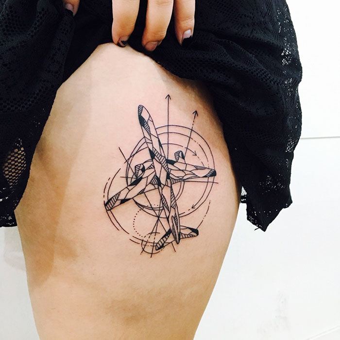 Abstract travel tattoo with airplane and geometric design on leg.