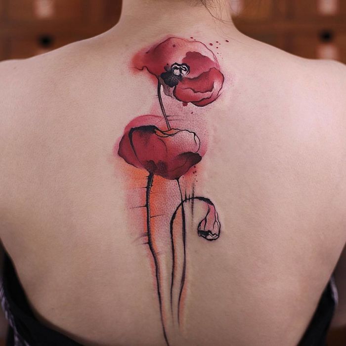 Watercolor tattoo of red poppies on a person's back, showcasing Chen Jie's artistry.
