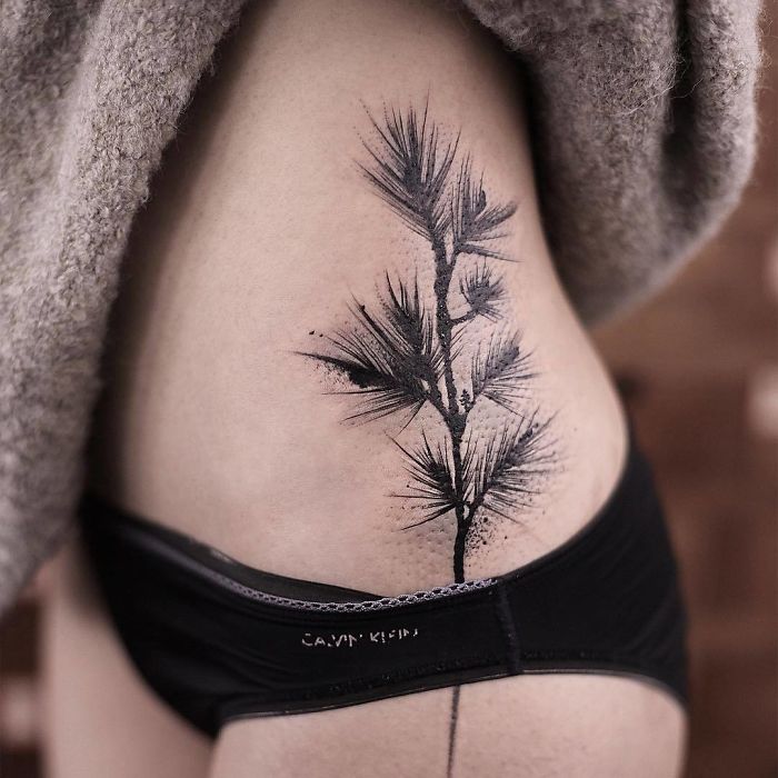 Watercolor tattoo featuring a delicate branch design on skin, showcasing Chen Jie's artistic style.