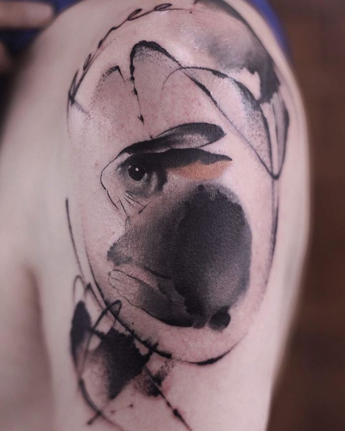 Watercolor tattoo by Chen Jie on an arm, featuring abstract brushstrokes and an eye.