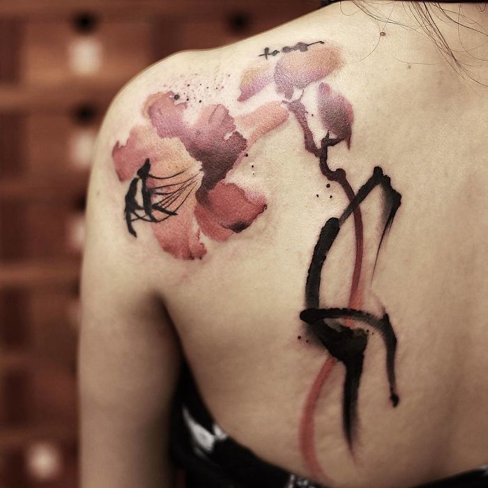 Watercolor tattoo by Chen Jie featuring a floral design on a person's shoulder.