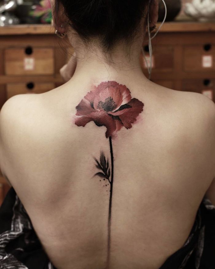 Watercolor tattoo by Chen Jie featuring a red poppy design on a person's back.