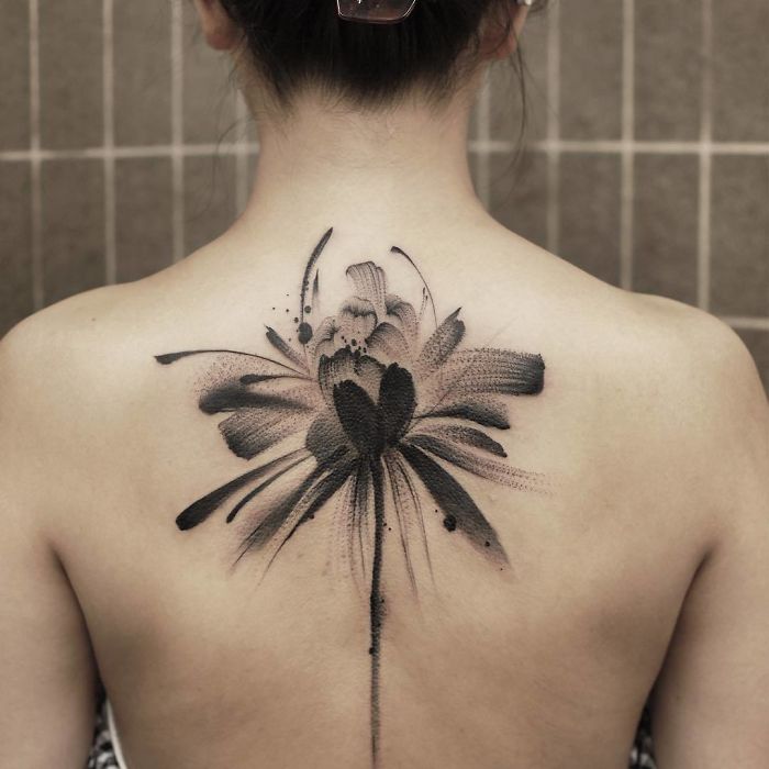 A watercolor tattoo by Chen Jie featuring a black floral design, elegantly inked on a person's back.