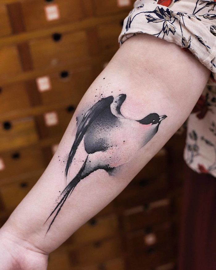 Watercolor tattoo of a bird on an arm, showcasing Chen Jie's artistic style.