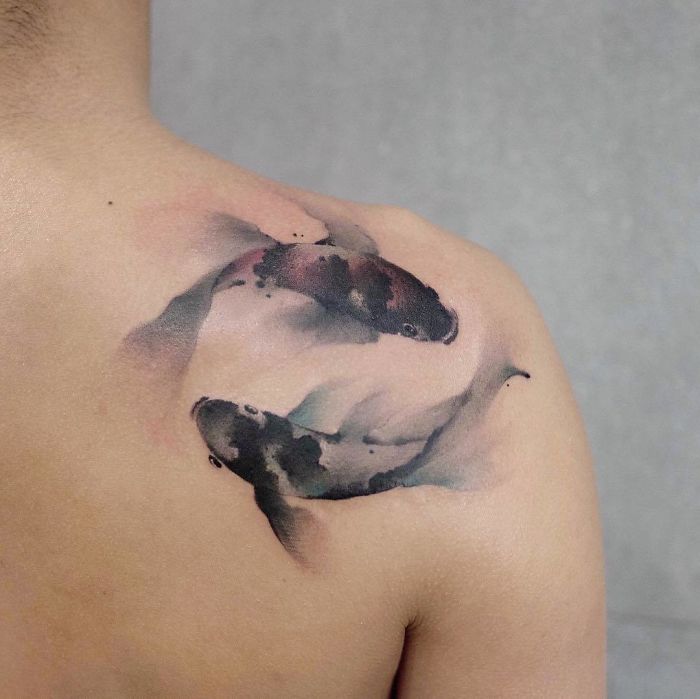 Watercolor tattoo of koi fish on a person's shoulder, demonstrating Chen Jie's artistic technique.