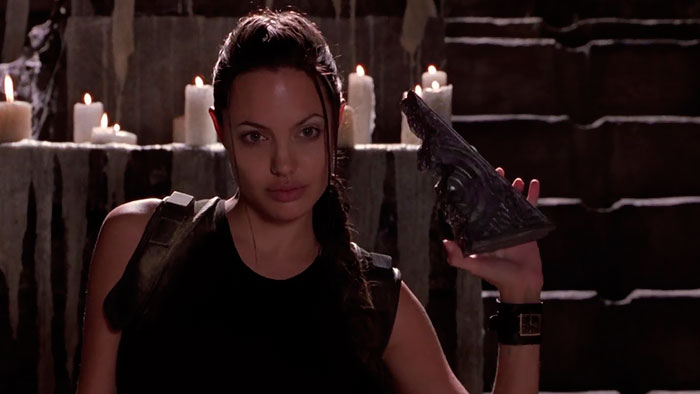 Lara Croft in Tomb Raider movie holding an artifact surrounded by candles, featured in fun facts about movies.