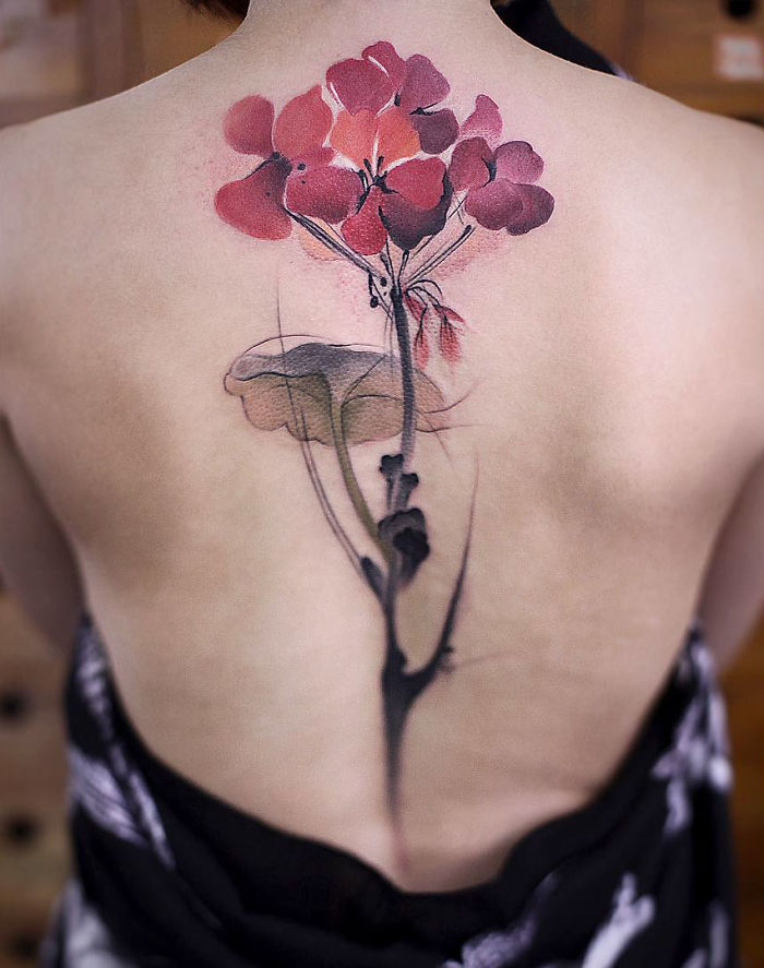 Watercolor tattoo of red flowers on a person's back, showcasing Chen Jie's artistic style.