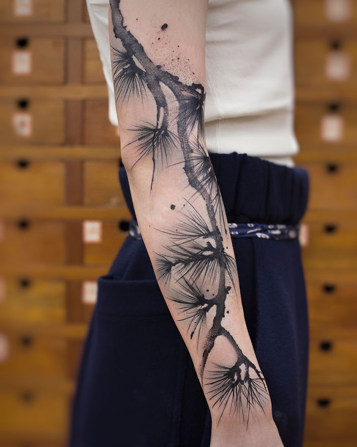 Watercolor tattoo on an arm by Chen Jie, featuring abstract black ink brushstroke design.
