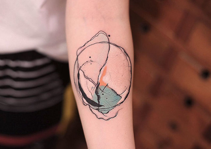Watercolor tattoo by Chen Jie on a forearm, featuring abstract shapes and soft colors.