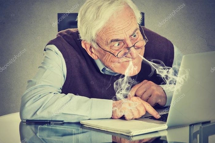 An old man with smoke coming from his nose sitting near laptop