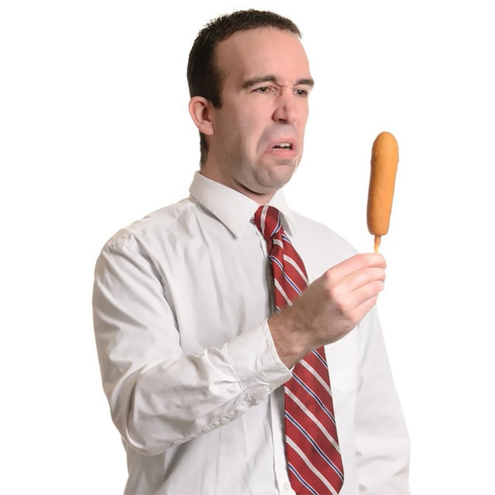 Man in a white shirt and red tie is disgusted by corndog