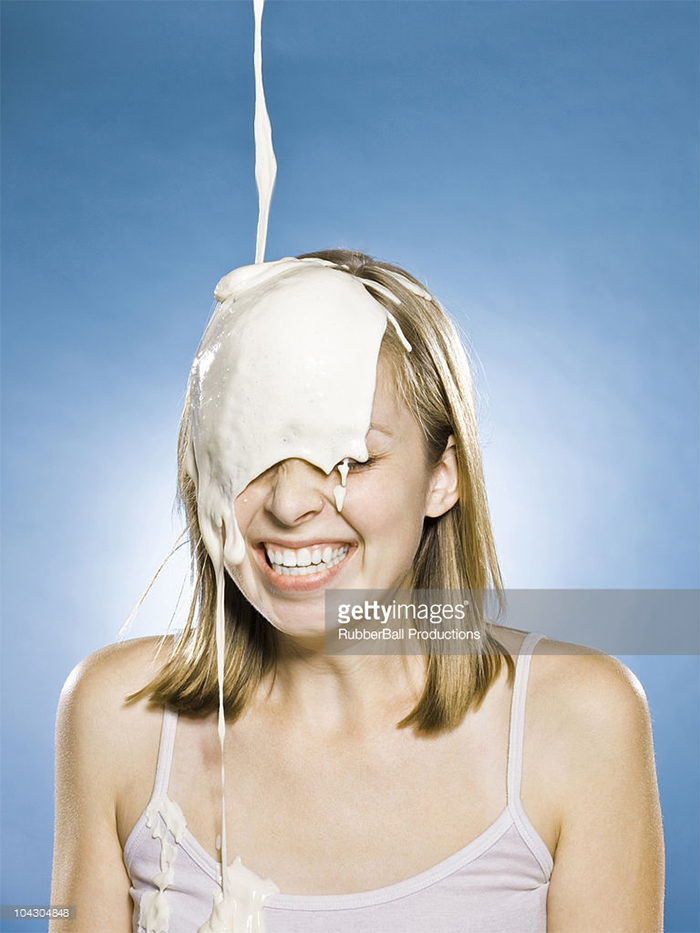 Happy young woman and yoghurt heavily dripping on her head