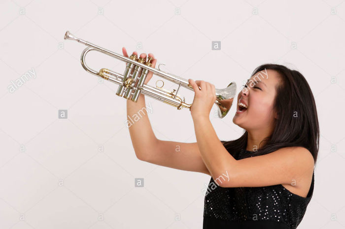 Asian girl screaming into a trumpet