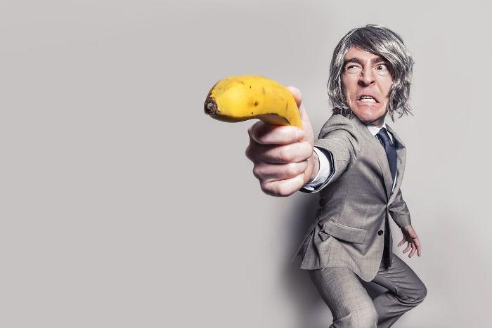 Man in silver suit attempting to shoot with banana