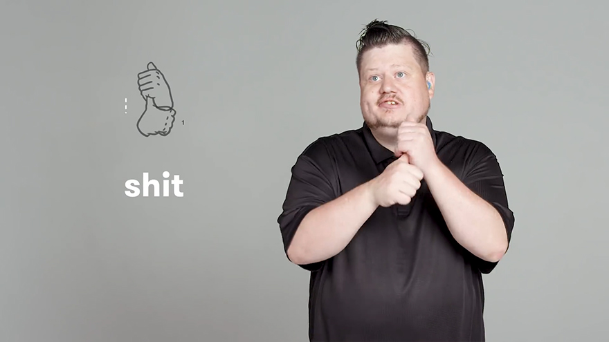 Person demonstrating sign language for a curse word against a gray background.