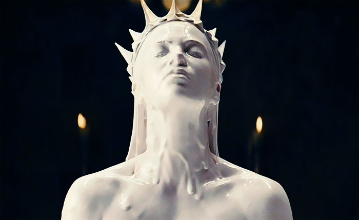 Scene from Snow White And The Huntsman movie featuring a statue covered in white wax in a dark setting, movie fun facts.