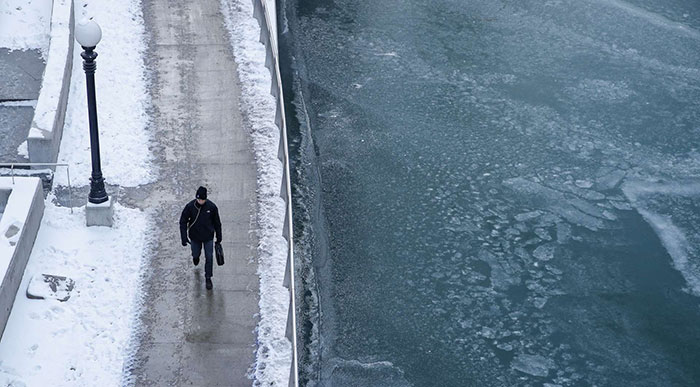 A Pedestrian Walks Along The Chicago River