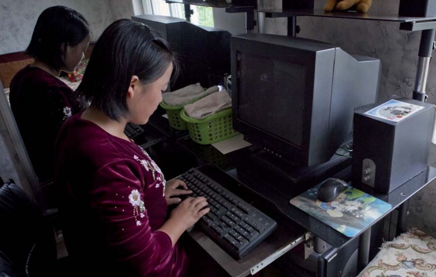 Two women typing something on the old black computers 