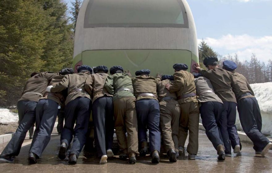 A group of men pushing a bus 