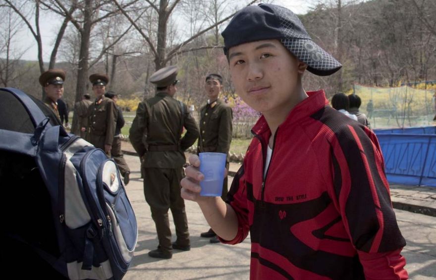 A kid holding a cup wearing a cap 