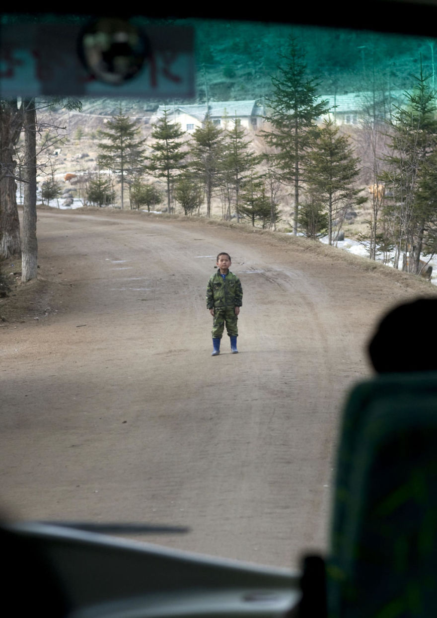 The kid standing in the middle of a road in front of a bus 