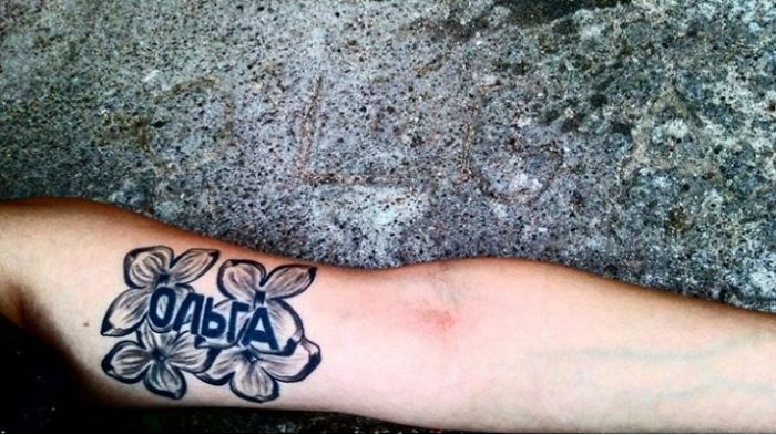 Tattoo of flowers and Cyrillic text on arm, showcasing personal story and design.