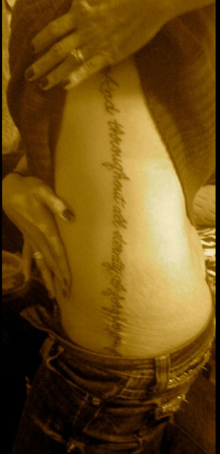 Script tattoo down a person's side, showcasing personal stories behind tattoos.