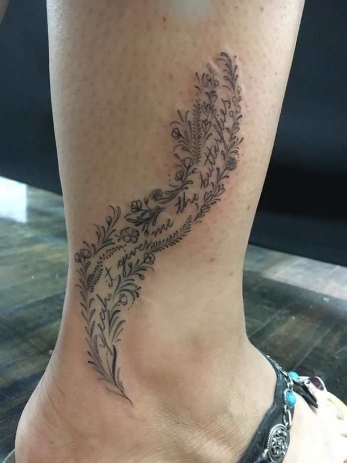 Floral tattoo with script on ankle, showcasing a personal story through intricate design.