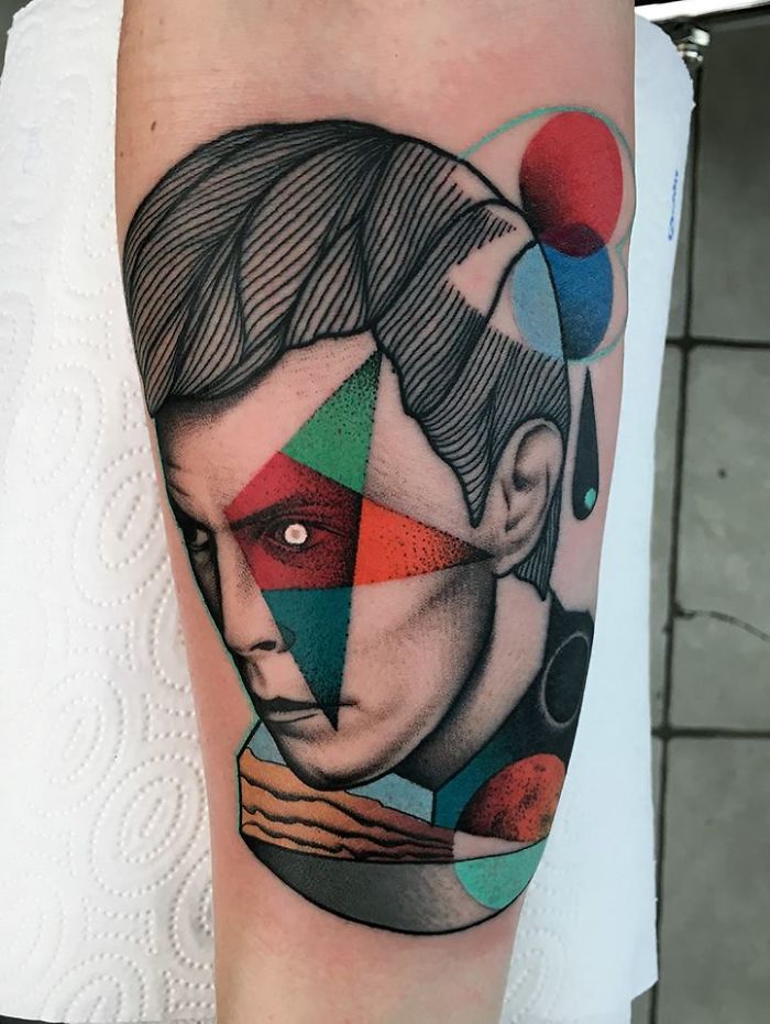 Abstract tattoo depicting human face with nature-themed geometric shapes and colors, highlighting relationship with nature.