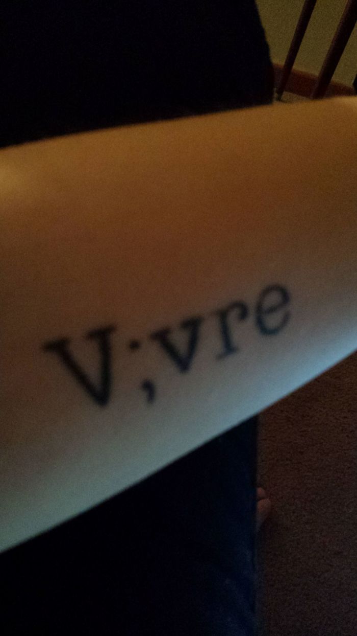 Tattoo reading "V;vre" on forearm, reflecting personal story behind the ink.