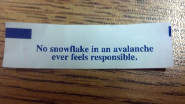 Sassy fortune cookie message: "No snowflake in an avalanche ever feels responsible," on a wooden table.