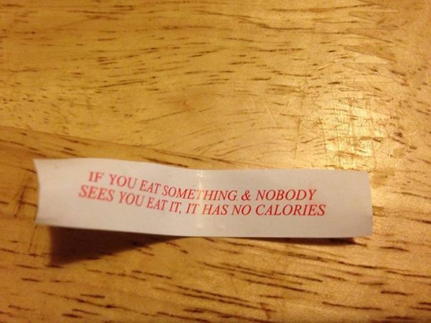 Fortune cookie message on table: "If you eat something & nobody sees you eat it, it has no calories." Sassy fortune saying.