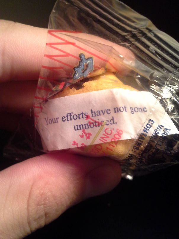 Fortune cookie saying: "Your efforts have not gone unnoticed," wrapped in a clear package held by a person.