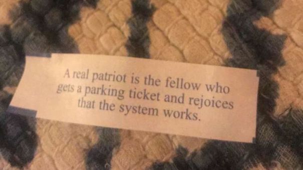 Sassy fortune cookie saying about patriotism and parking tickets on textured fabric background.